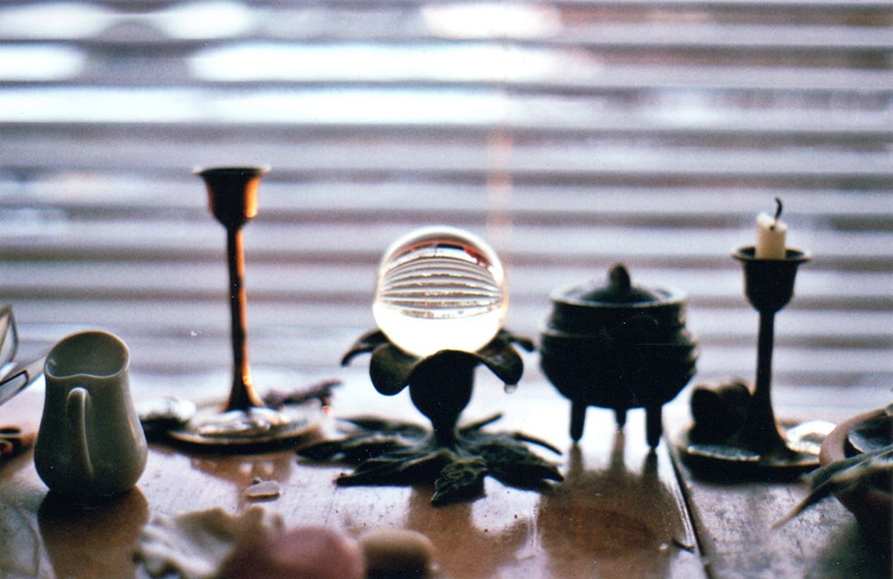 A crystal ball sitting in a window. A small cauldron on a table